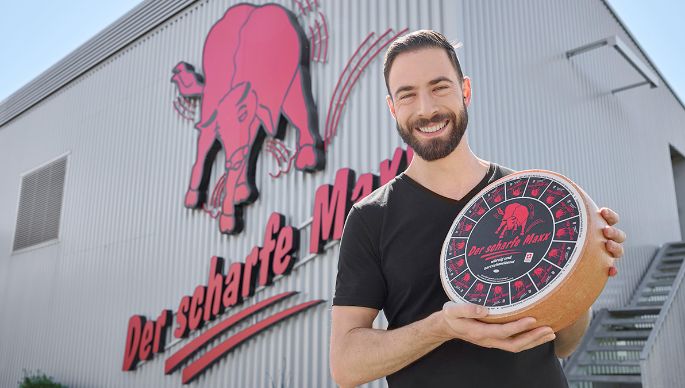 Mister Maxx 2025 mit einem Käselaib Der scharfe Maxx in der Hand.