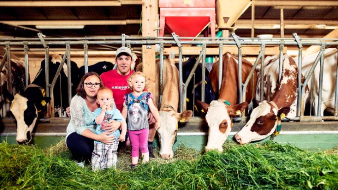 Bauernfamilie mit zwei Kindern im Kuhstall 