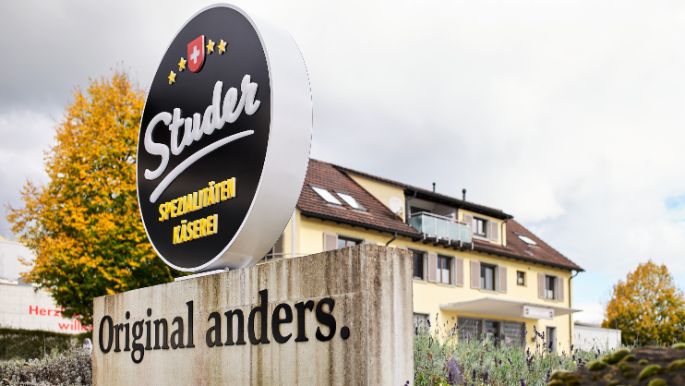 Firmenschild mit Logo vor dem Gebäude der Käserei Studer