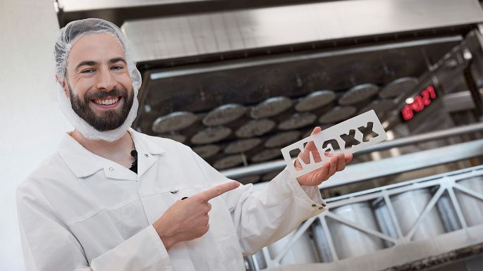 Mister Maxx 2025 mit dem Brandingschild für den Käselaib Maxx in der Hand.